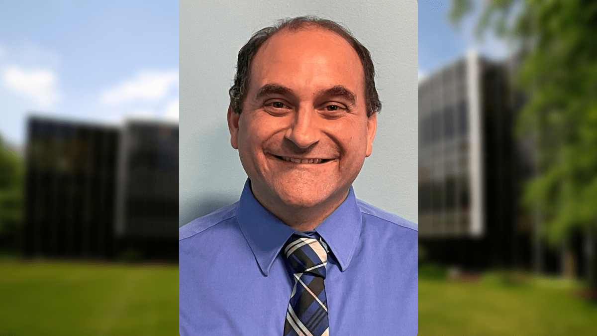 A man is smiling and wearing a tie